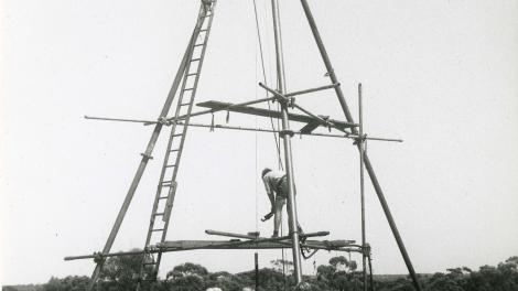 A black and white picture from the early 1960s of a large wooden drilling frame