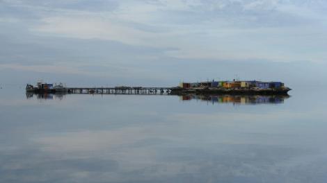 An island fishing settlement reflecting on a calm ocean