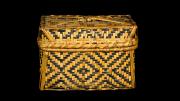 A lidded, rectangular, black and natural coloured basket  with a diamond design.