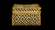 A lidded, rectangular, black and natural coloured basket  with a diamond design.