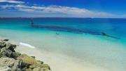 Image of beach with shipwreck offshore in shallow water