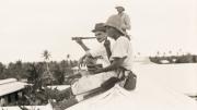 Two people sitting on a roof top watching a naval battle