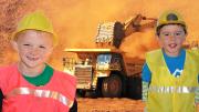 Two children wearing safety gear in front of a large mine