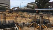 Concrete foundations in a square formation with yellow barriers around them. 