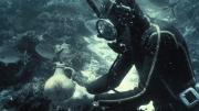 Person underwater in diving suit holding an object