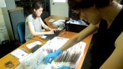 Image of a person going through a box filled with badges in clear plastic bags. 