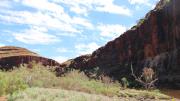 A large dark gorge overlooking a pool of water during the day