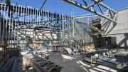 The sky can be seen from a concrete room divided by steel trusses.