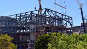 A crane lowers the last section of steel onto a steel frame of the building 