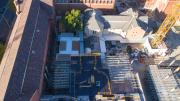 birds eye view of construction site shows scaffolding around new section of building surrounded by heritage buildilngs