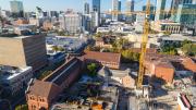 view of construction site and large yellow crane with city and surrounding buildings in background