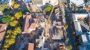 Looking down from above.  Heritage buildings are the left of the photo, a crane in the middle and construction and scaffolding materials to the right. 