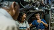 Two visitors laughing as their HMAS Ovens tour guide regales them with stories.