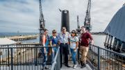 A tour group stand for a photo in front of the HMAS Ovens.