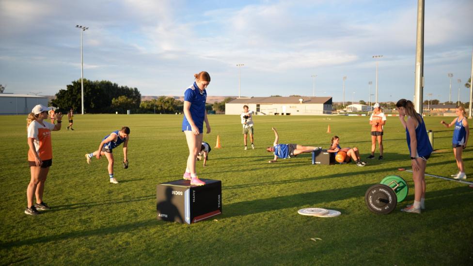 A group of sportspeople on a sporting field performing various training activities