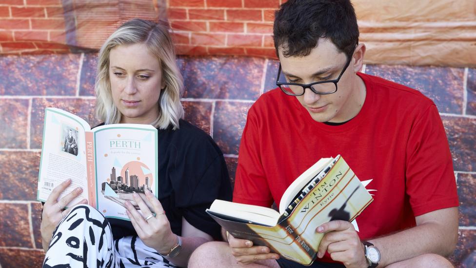 "A man and a woman reading Western Australian literature outside the Inflatable Museum."