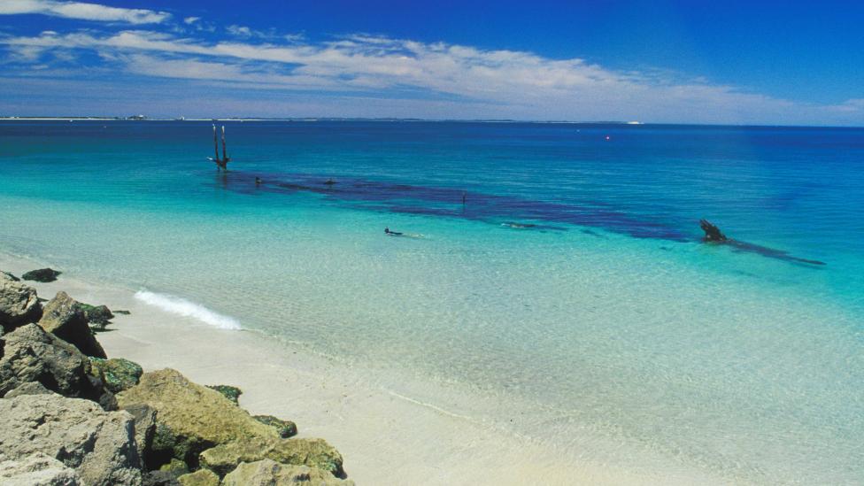 Image of beach with shipwreck offshore in shallow water