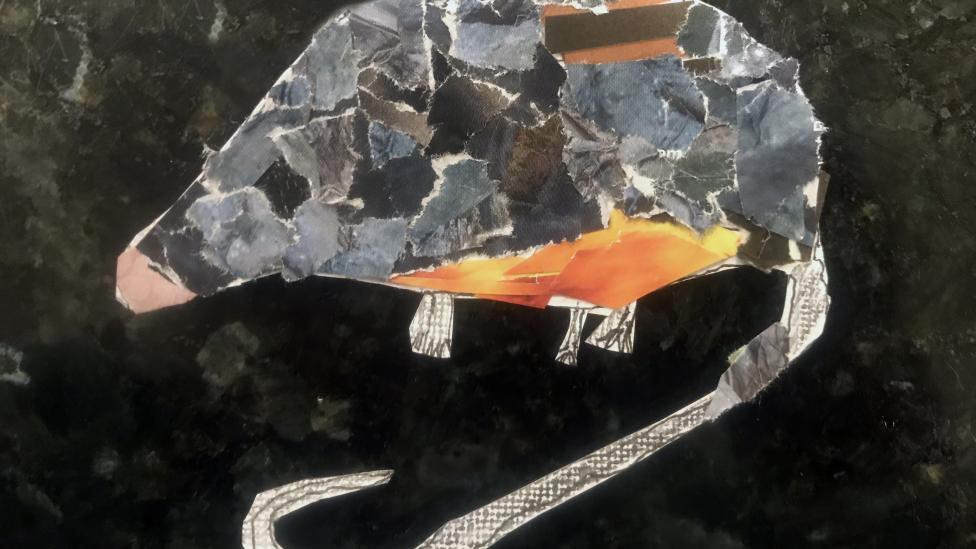 "Light and dark grey, and orange pieces of paper make up the shape of a possum."
