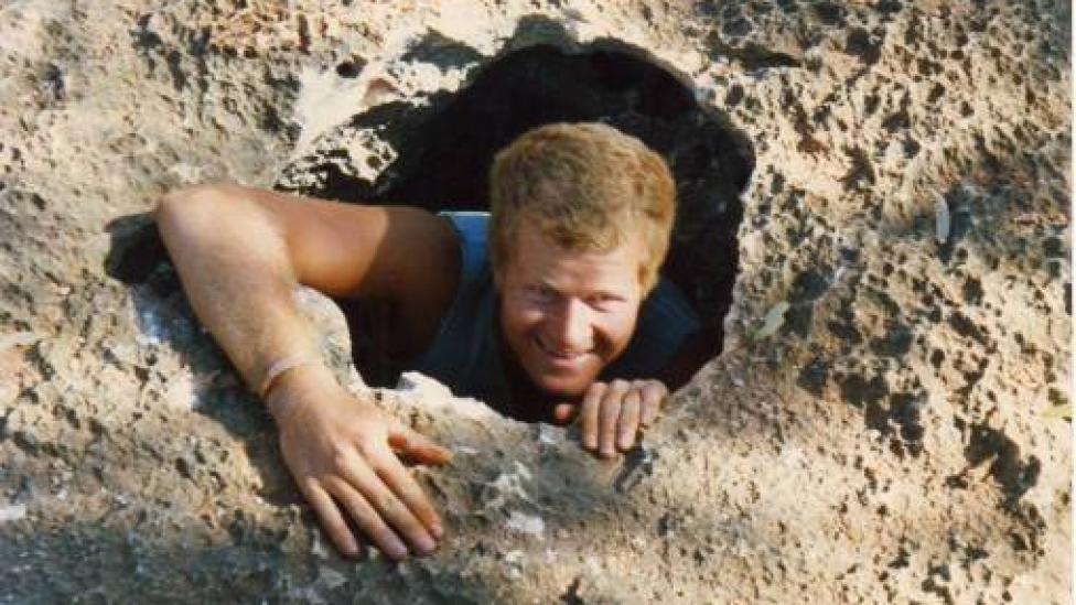 Photo of a man climbing out of a hole taken during a subterranean biology field trip.