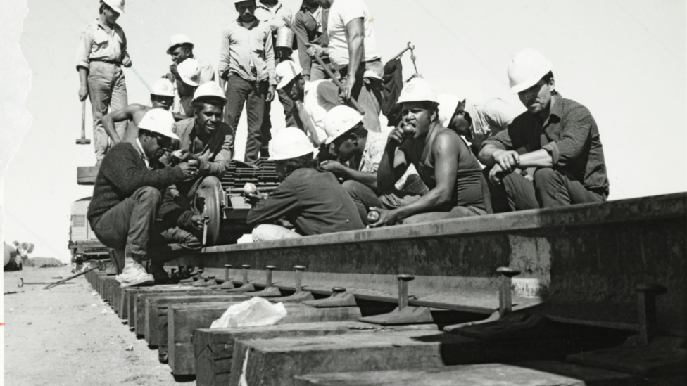 "A group of workers stop of a break on top of a railway line."