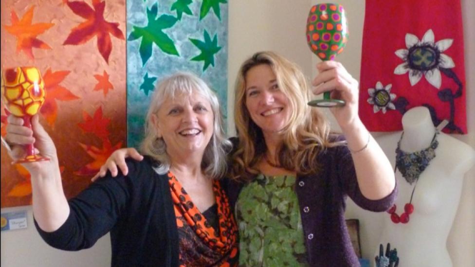 Two women surrounded by art and craft works