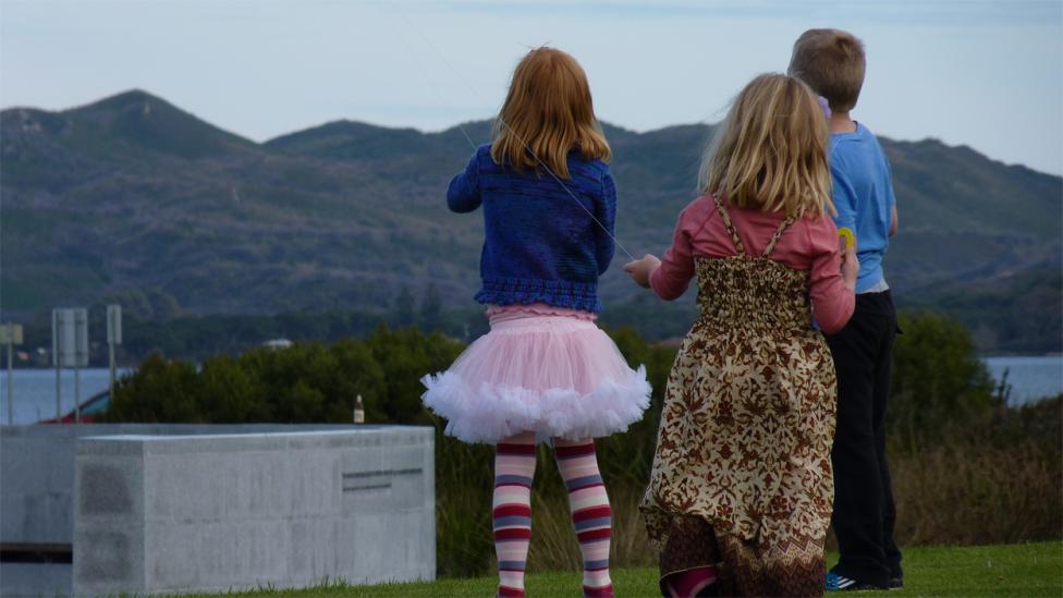 Three children flying a kite near the coastline