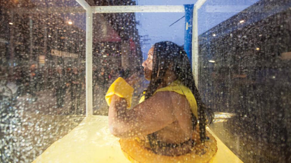 "A woman sitting in an enclosed tank of water."