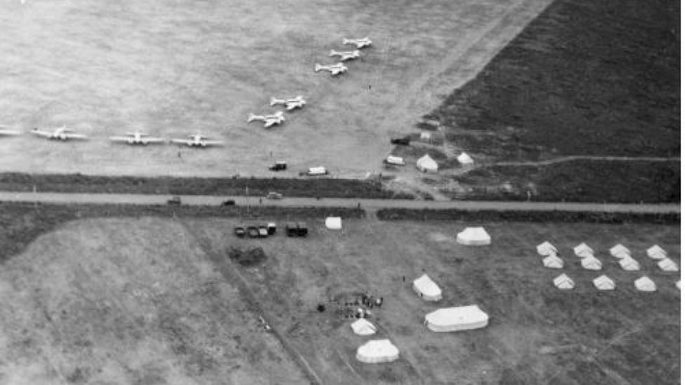 A black-and-white aerial photograph of aeroplanes in a field