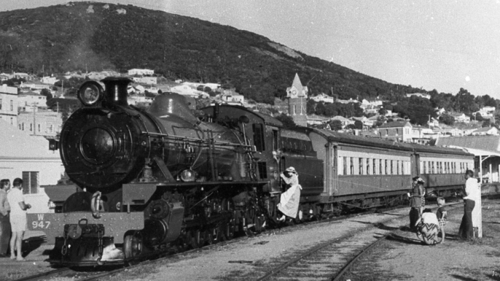 A black-and-white photograph of people boarding a train