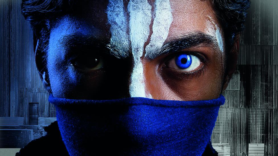 The top half of a young man's face, he has one striking blue eye, white paint markings on his face and is wearing a blue mask that covers his nose and mouth.