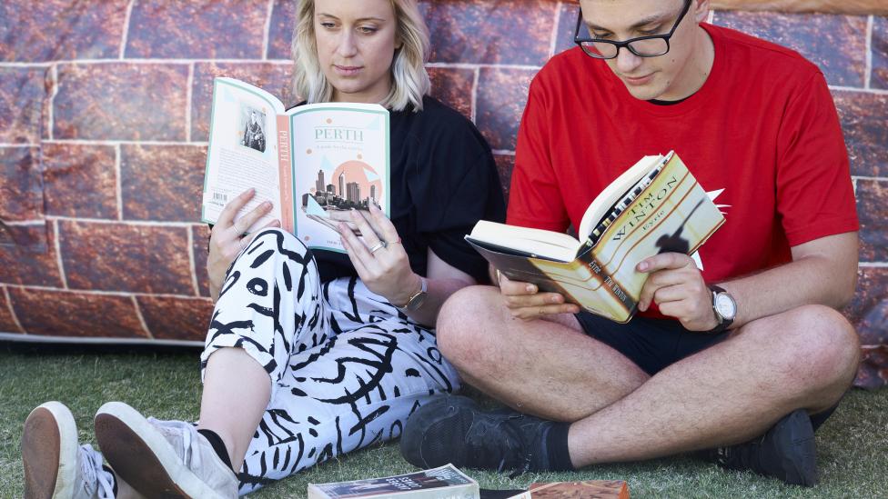 A man and woman reading books about Western Australia