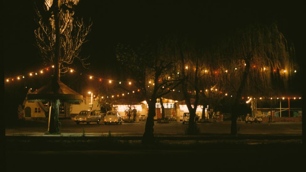 Bernies from afar at night time with its lights on, surrounded by festoon lights