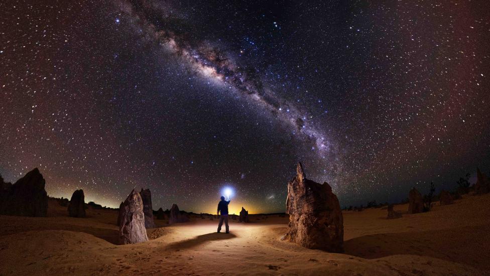 Man standing under night sky at Nambung National Park.