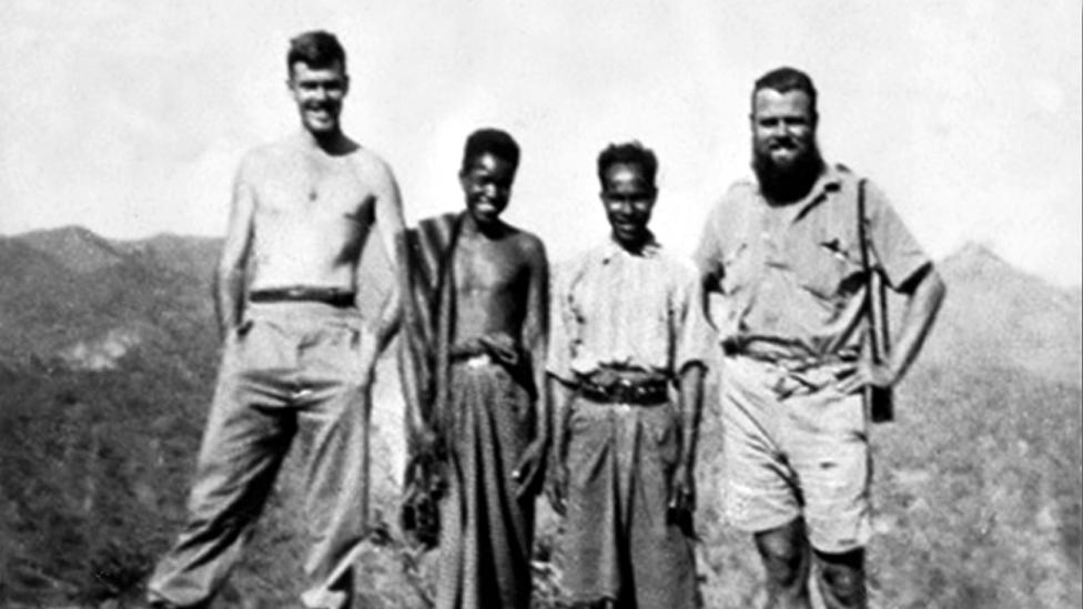 Two Australian soldiers standing with two young East Timorese men, known as criados