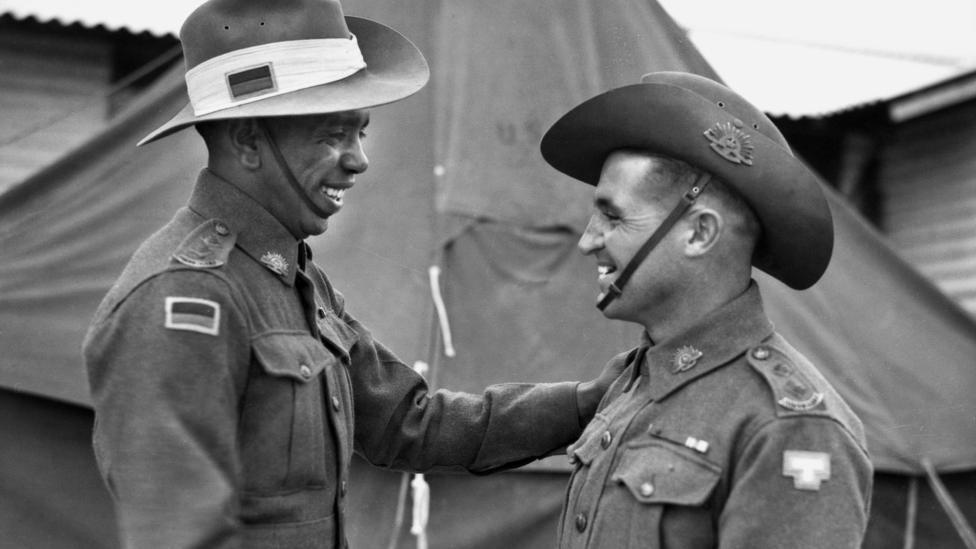Lieutenant Reg Saunders (left) and Lieutenant Tom Derrick VC DCM, congratulate each other face-to-face following their graduation from the Office Cadet Training Unit at Seymour, 25 November 1944.