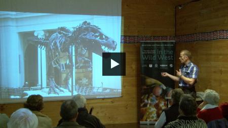 Mikael Siversson presenting a slideshow with a slide of a T-Rex fossil